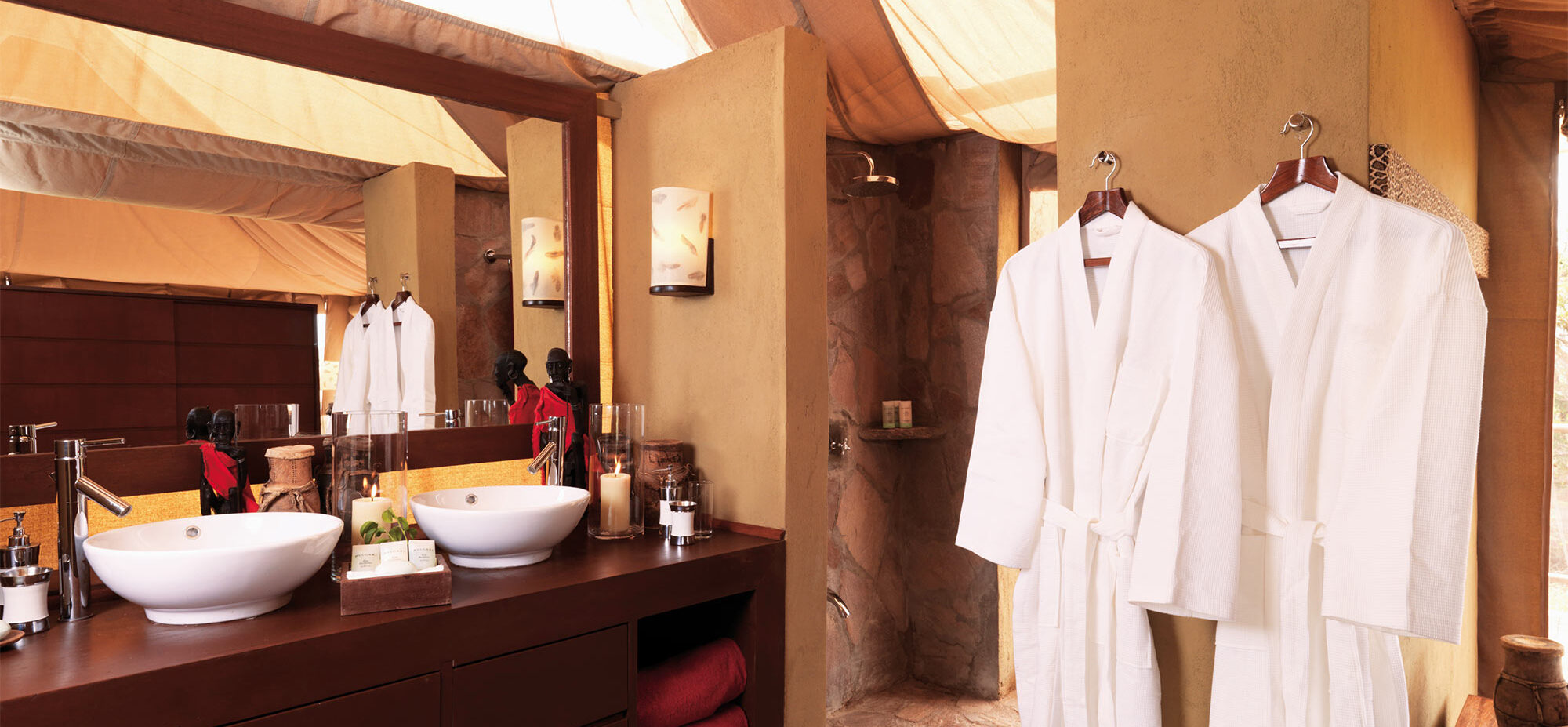 Two robes hanging in the bathroom with the his/hers sinks in the background