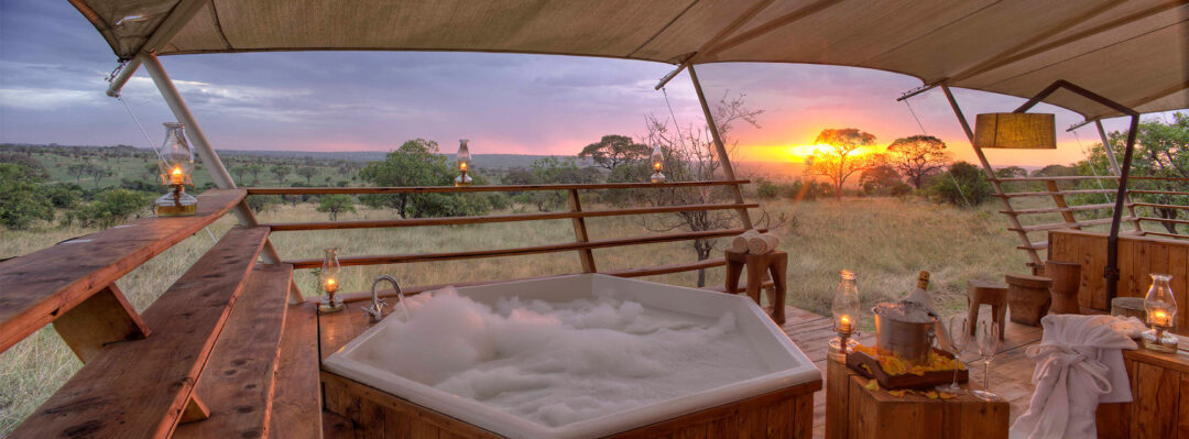 Bubbling hottub on the deck of the tent with the sun setting in the background