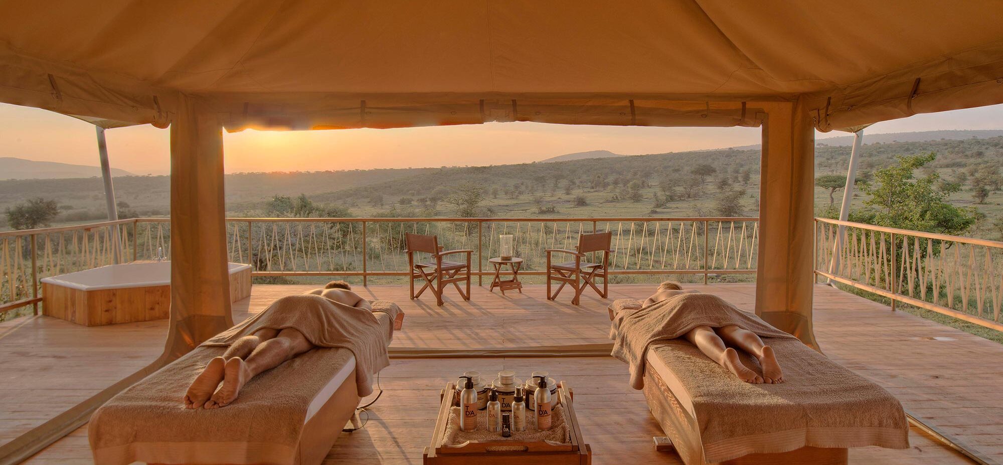 A couple lay on two massage beds at sunset