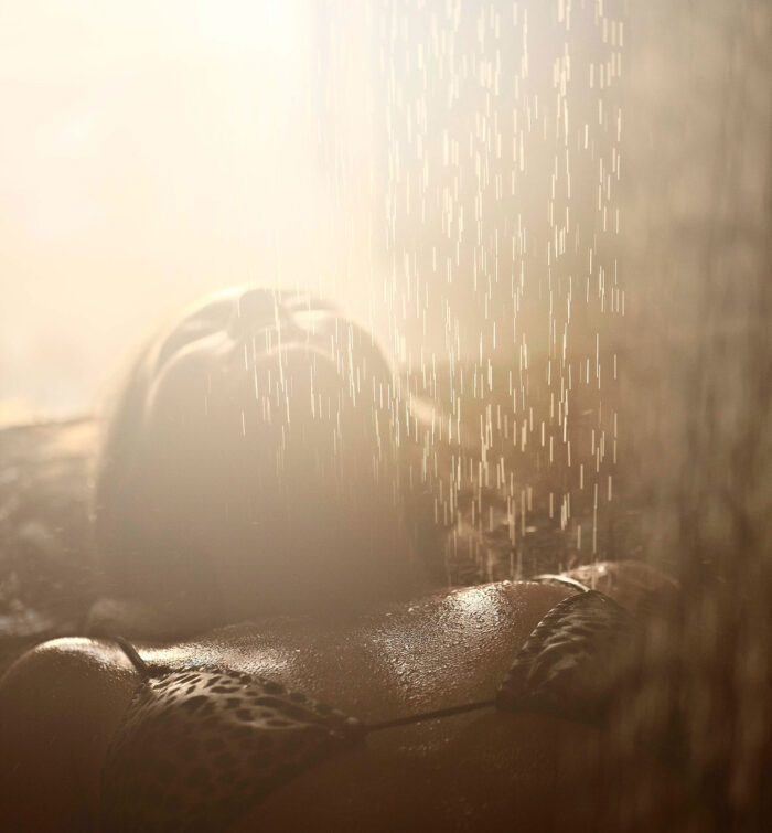 A women laying under a steam of water