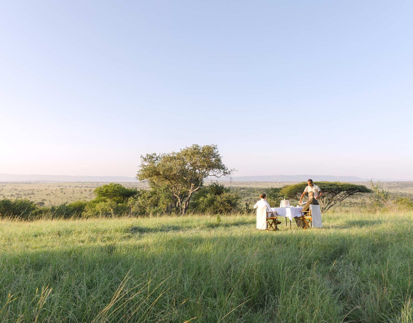 A man serving a couple breakfast in the grass