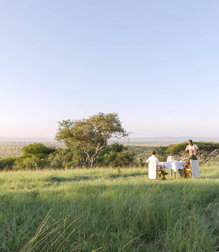 A man serving a couple breakfast in the grass