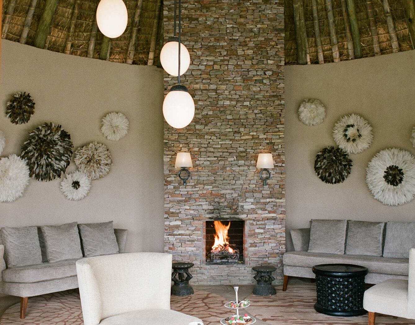 A white chair beside a coffee table with a stone fireplace in the background