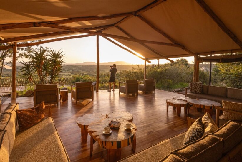 Luxury safari camp overlooking the African savanna at sunrise, featuring elegant tented accommodations, expansive wildlife views, and a serene natural setting.