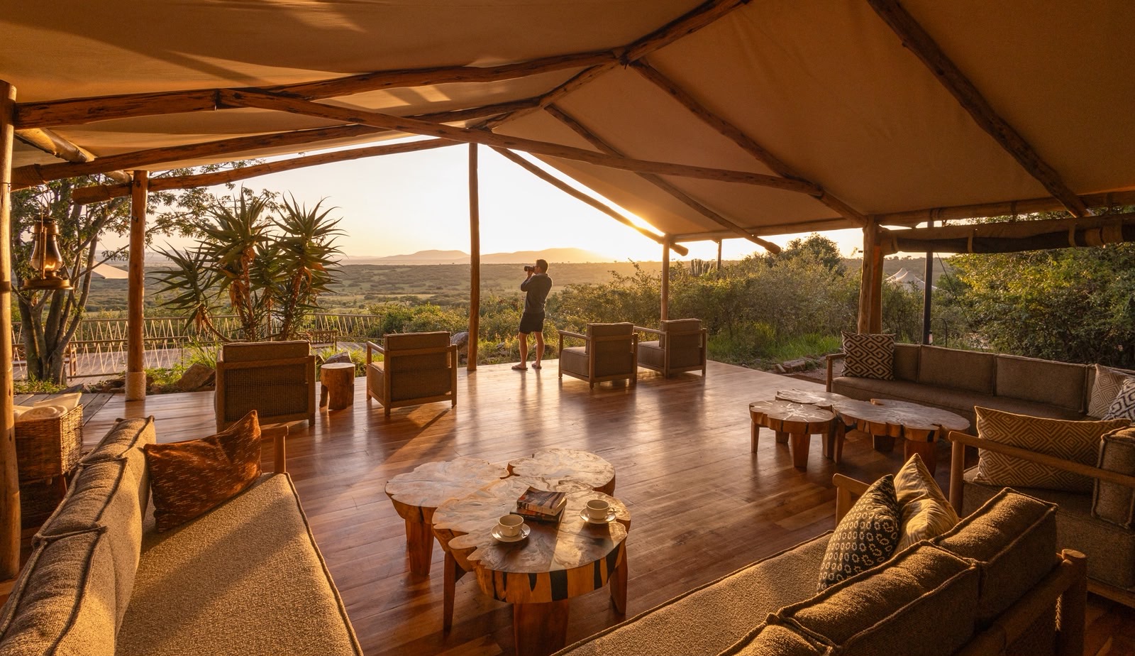 Luxury safari camp overlooking the African savanna at sunrise, featuring elegant tented accommodations, expansive wildlife views, and a serene natural setting.